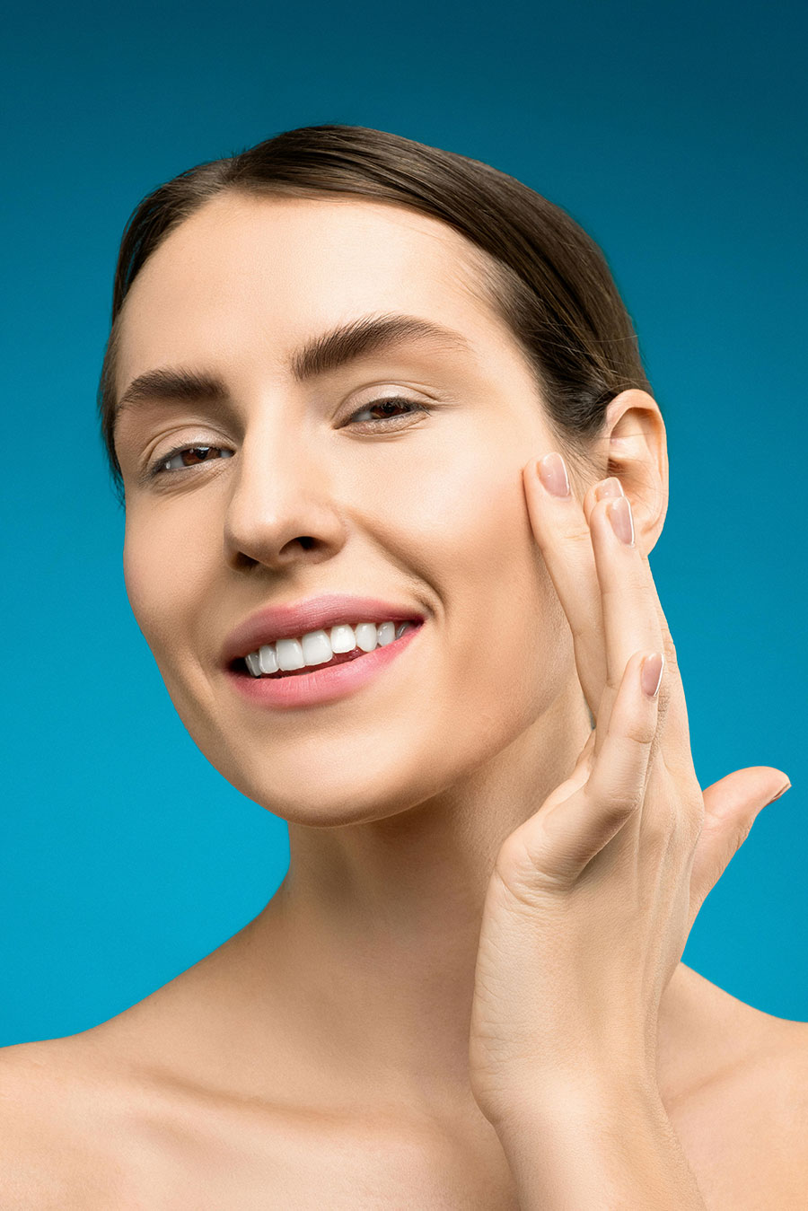 A smiling woman examines her clean, smooth face