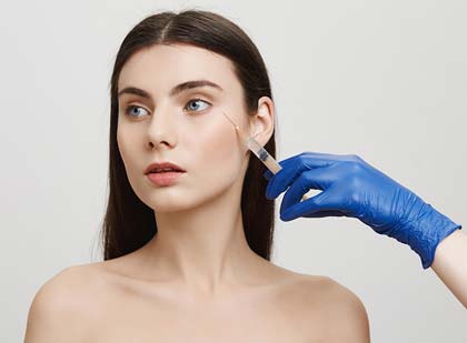 A smiling woman receives medical botox treatment from a professional