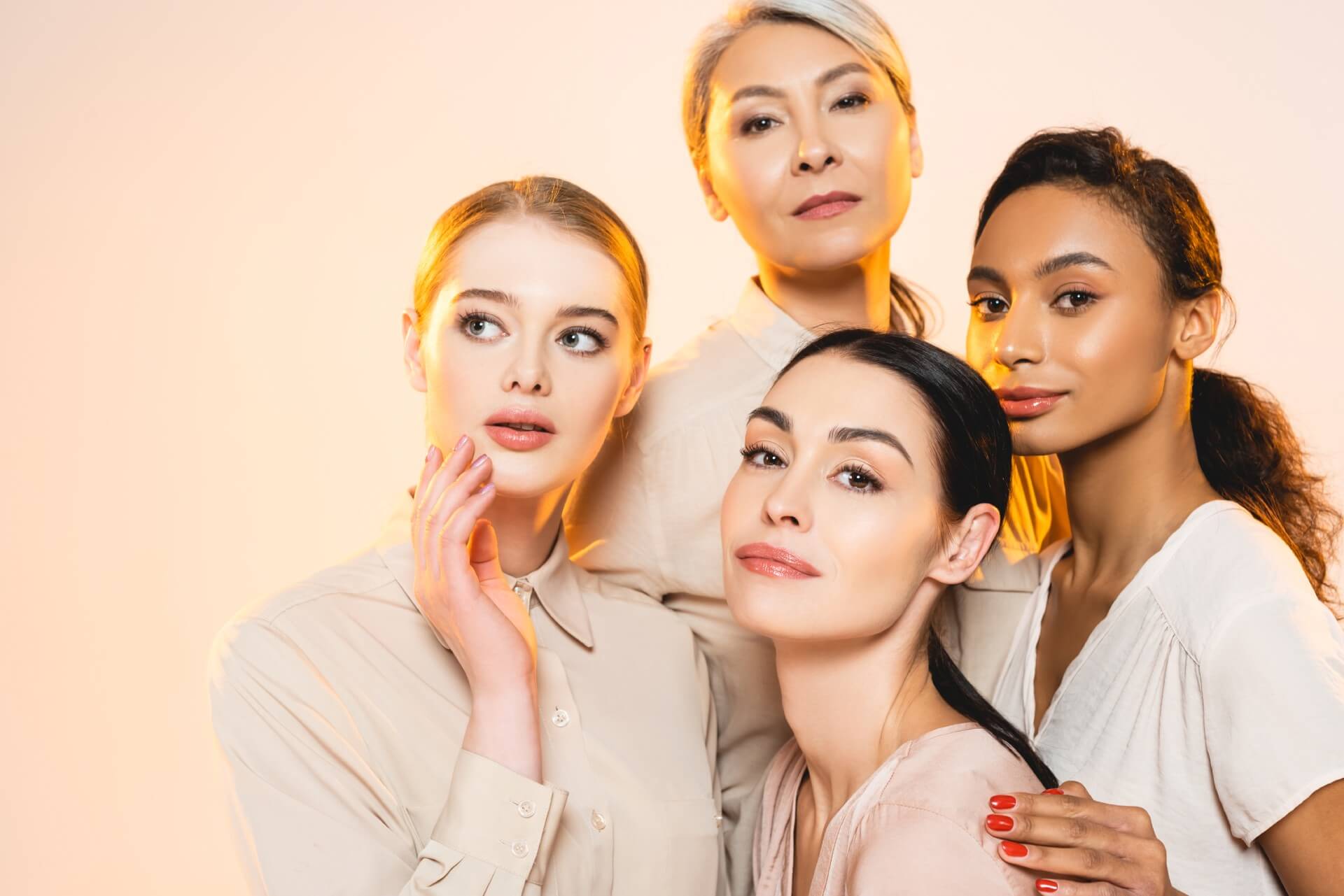 Four diverse women stand close together, bathed in golden light