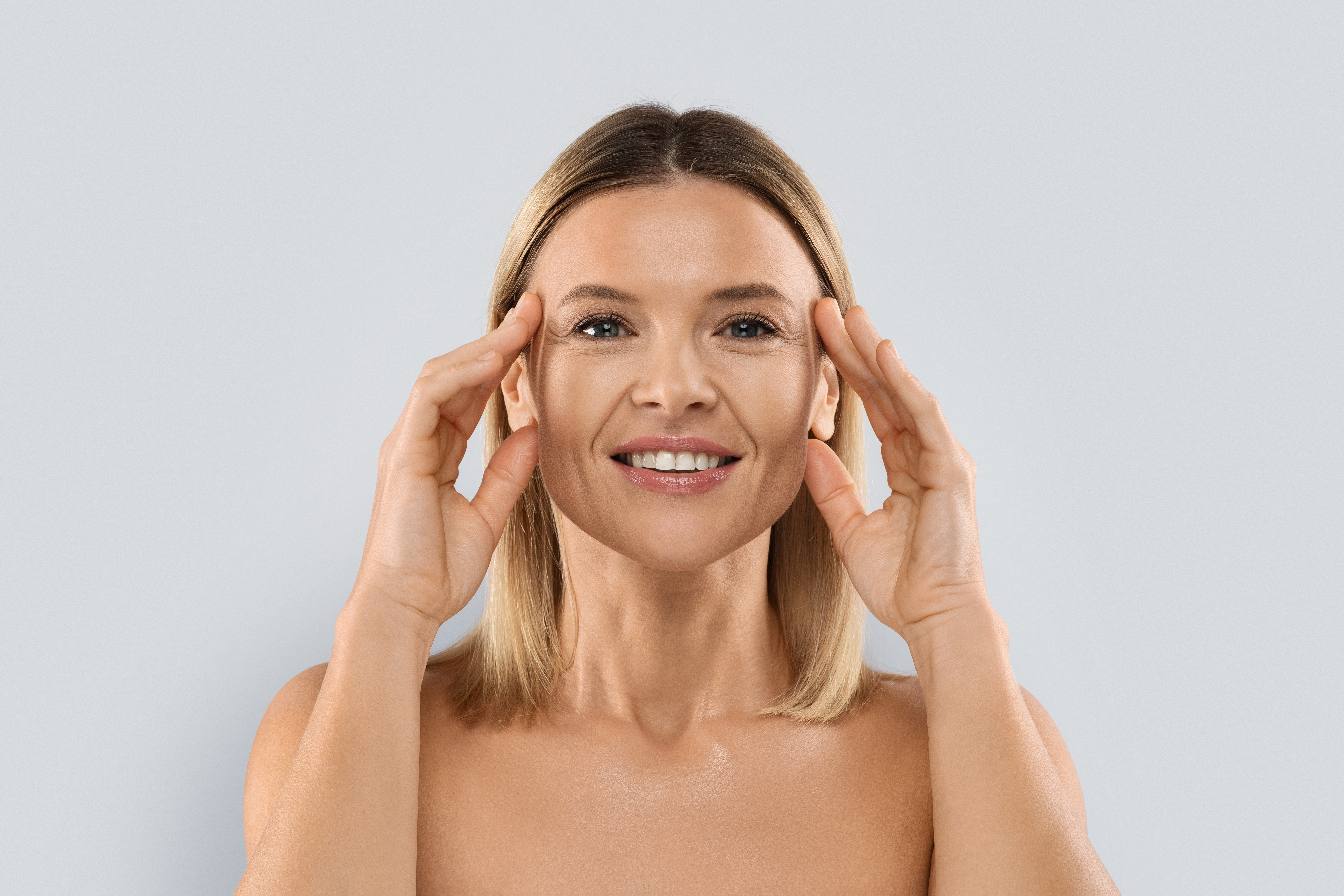 A smiling woman pressing her fingers gently to her temples