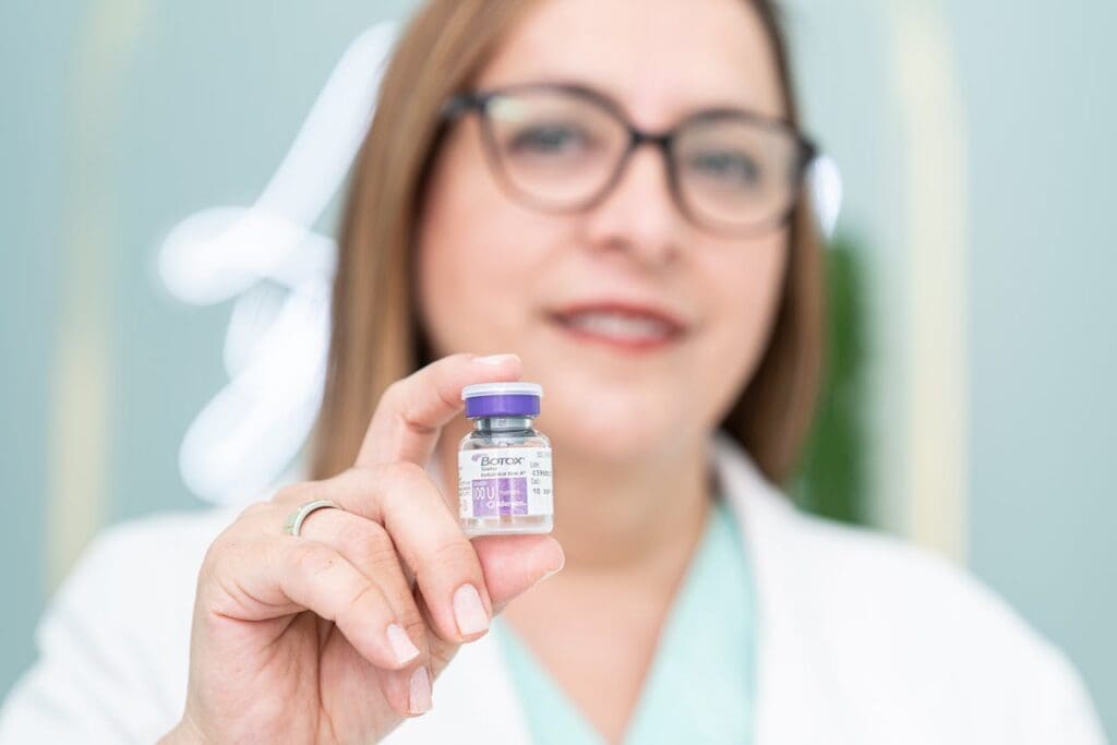 Smiling medical professional holding a Botox bottle in focus