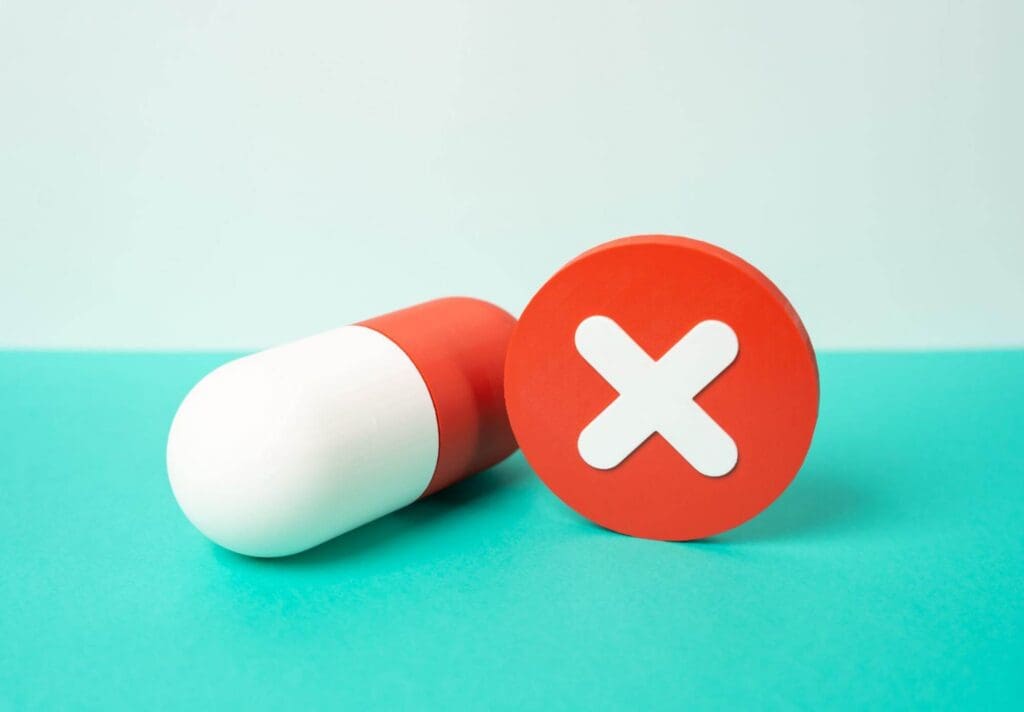 An oversized red and white pill next to a red and white X